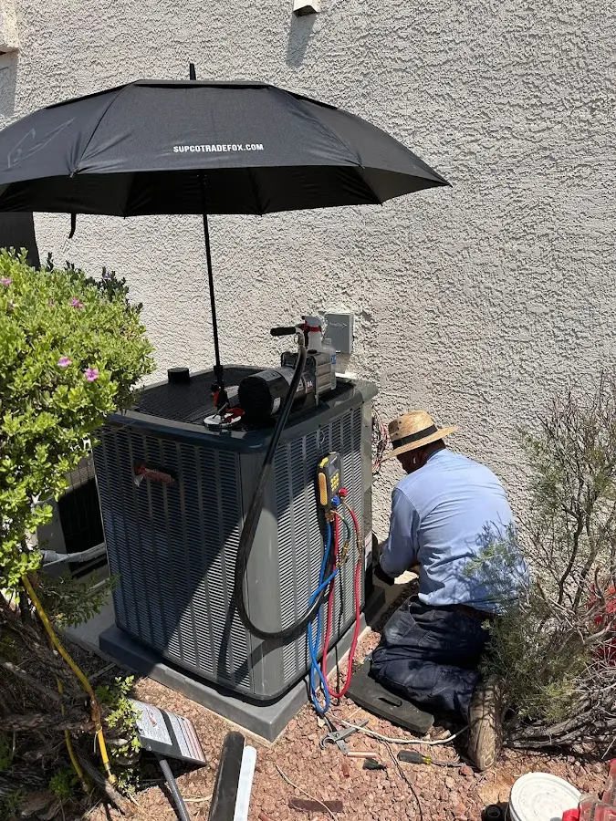 HVAC technician performing outdoor AC maintenance in Barstow
